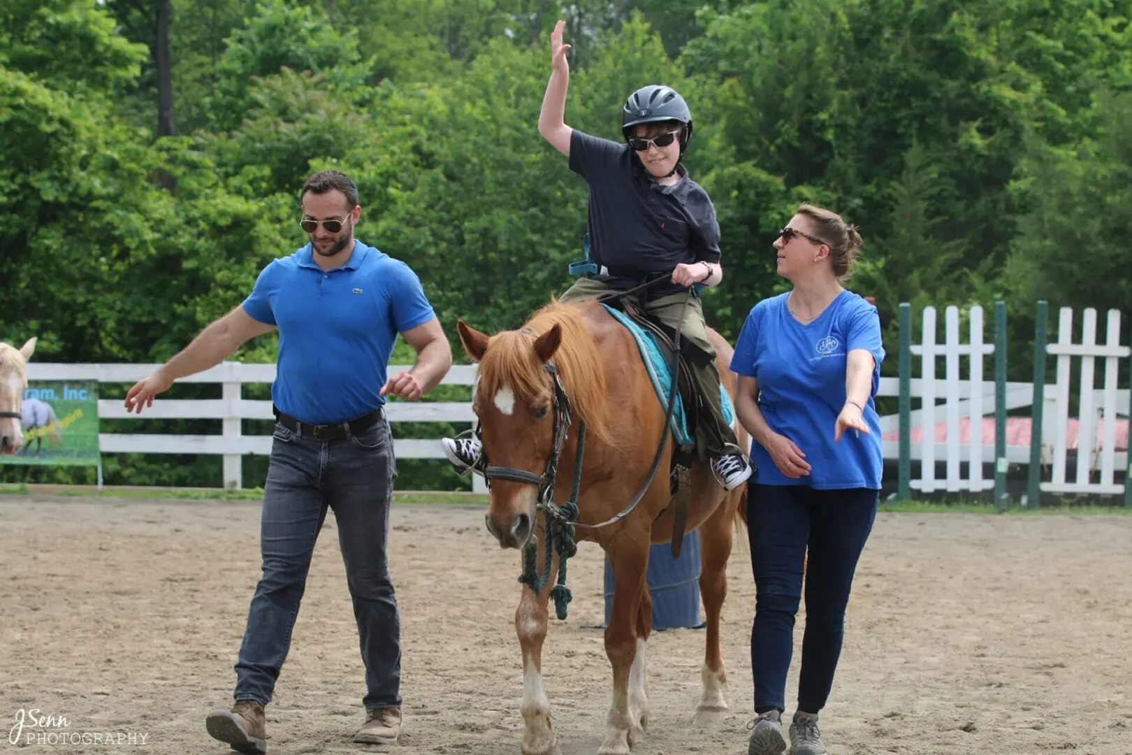 A boy in a helmet riding a horse and two adults